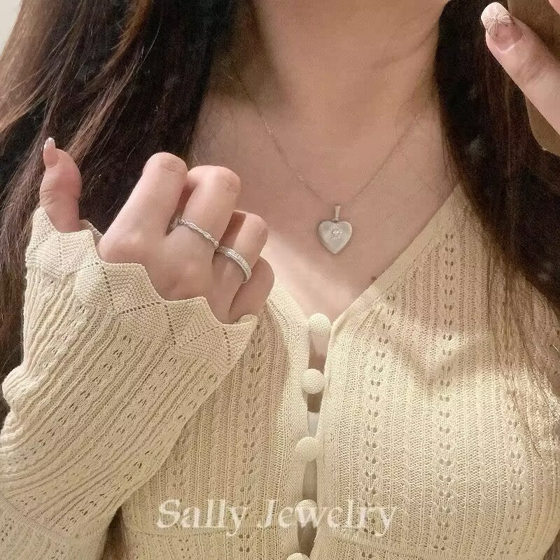 A model wearing the Heart Brushed Necklace in silver. The necklace features a heart-shaped pendant with a brushed matte finish. The model’s neck is gently posed, highlighting the elegant and minimalist design of the silver pendant.