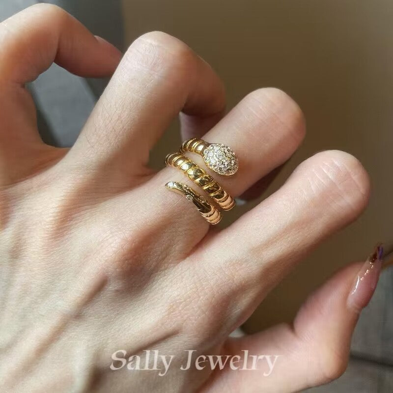 A close-up of the Striped Snake Head Ring worn by a model, showcasing its bold serpentine design with intricate striped detailing. The ring’s striking snake-head shape adds an edgy, statement-making touch to the model's hand, combining modern elegance with a hint of fierceness.