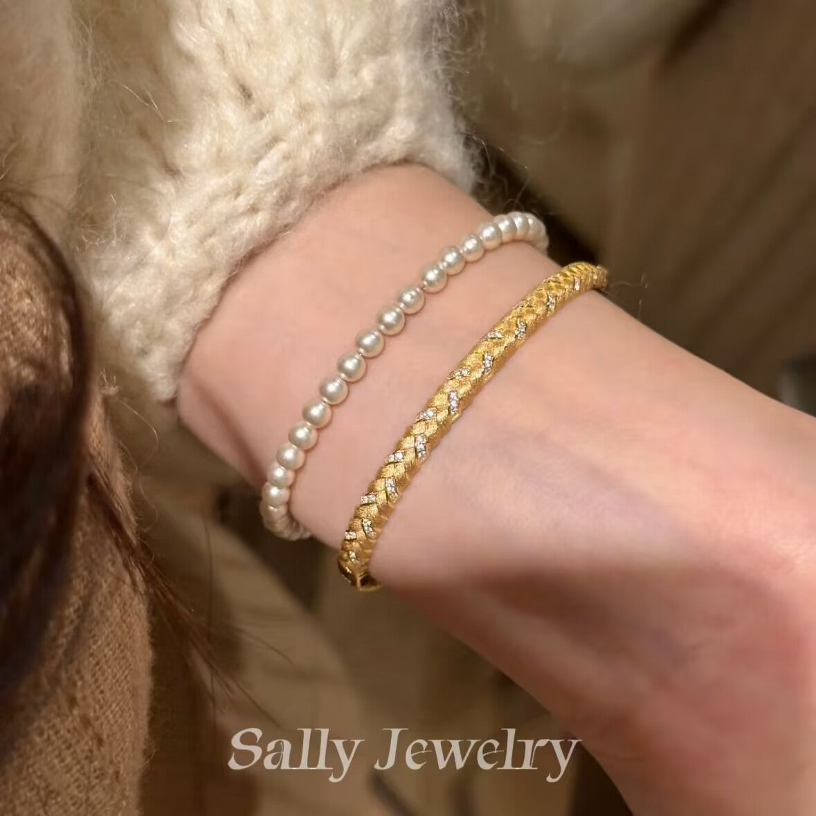 A close-up of the Wheat Brushed Bracelet in gold, worn on a model's wrist. The bracelet features a textured, brushed design inspired by wheat stalks, with the rich gold finish adding a touch of warmth and elegance to the model's sophisticated look.