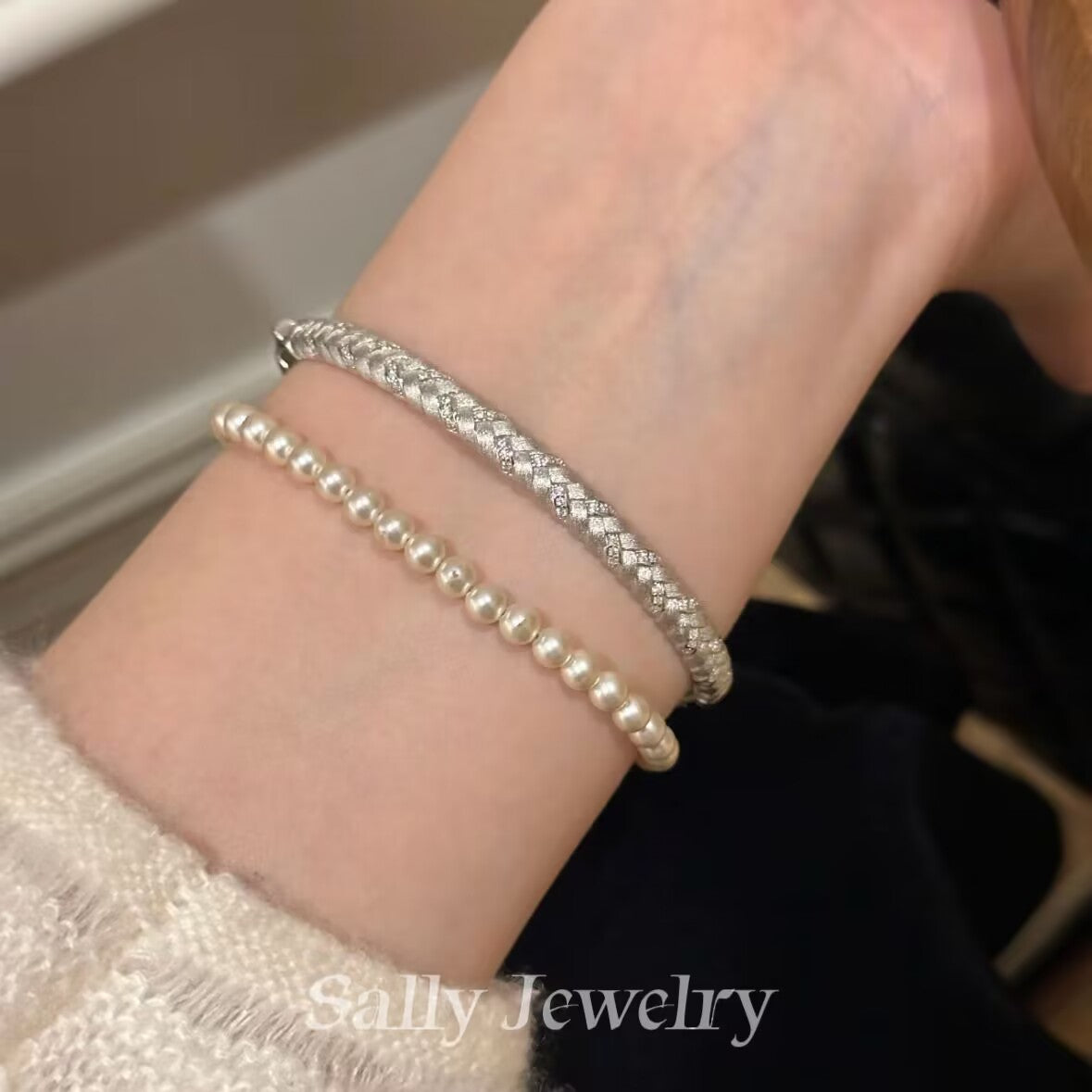 A close-up of the Wheat Brushed Bracelet in silver, worn on a model's wrist. The bracelet features a textured, brushed design resembling wheat stalks, with the sleek silver finish giving it a refined, modern look that adds elegance to the model’s overall style.